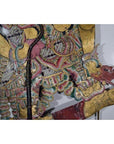 Balinese cowhide wayang kulit shadow puppet with ornate patterns and dragon-shaped foot on white background.