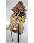 Close-up of ornate Wayang Kulit Balinese shadow puppet made from cowhide, holding two sticks against white background.