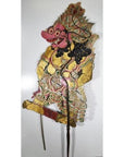 Close-up of ornate Wayang Kulit Balinese shadow puppet made from cowhide, holding two sticks against white background.