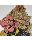 Pink cowhide Wayang Kulit shadow puppet with bulging eyes and ornate headdress on white background.