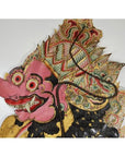 Pink cowhide Wayang Kulit shadow puppet with bulging eyes and ornate headdress on white background.