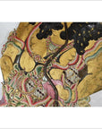 Gold-accented cowhide Wayang Kulit shadow puppet with intricate patterns, elaborate costume, close-up.