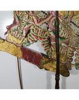 Gold and brown cowhide wayang kulit shadow puppet with ornate patterns on a white background.