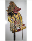 Close-up of red and yellow Wayang Kulit Balinese cowhide shadow puppet with intricate patterned clothing.