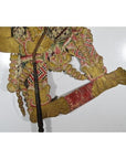 Colorful cowhide Wayang Kulit Balinese shadow puppet with bare feet on a plain white background.
