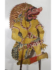 Yellow cowhide Wayang Kulit Balinese shadow puppet with red face and ornate headdress, close-up view.