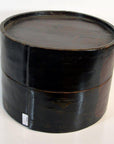 Light and dark wood round hat box with fitted lid, vintage style, close-up on plain white background.