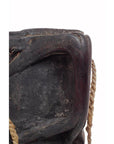Close-up of dark wood Indian pitcher with textured surface and rope handles.
