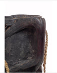 Close-up of dark wood Indian pitcher with textured surface and rope handles.