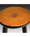 Close-up of a round brown wooden Antique Indonesian stool seat with rustic, scratched, and worn surface.