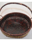 Dark brown woven bamboo offering basket with sturdy handle, close-up against a plain light background.