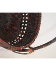 Close-up of natural bamboo offering basket with curved handle and intricate hand-woven texture and pattern.