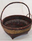 Red and gold woven bamboo offering basket with curved handle, close-up on white background.