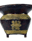 Black and gold woven bamboo offering basket with embossed floral design and four short legs, close-up.