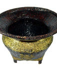 Close-up of ornate gold and black woven bamboo offering basket with gilt décor, wide rim, raised patterns, four short legs.