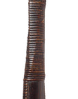 Close-up of dark brown ribbed wood woven long handle basket with horizontal grooves, on a white background.