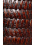 Close-up of dark brown wooden woven long handle basket with carved chevron and woven pattern.