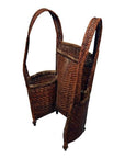 Natural rattan woven carrying basket with two tall handles and four small legs, close-up studio view.