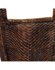 Close-up of natural rattan woven basket with sturdy handles and rustic texture against a white background.