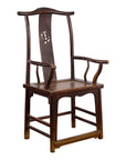 Dark wood Qing Dynasty scholar's armchair with carved splat, next to an antique leather trunk, studio setting.