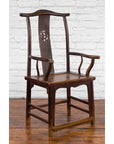 Dark wood Qing Dynasty scholar’s armchair with carved splat next to an early 20th-century Chinese trunk.