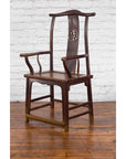 Dark wood Qing Dynasty armchair with carved splat beside early 20th century Chinese trunk on wooden floor.