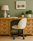Bleached teak kneehole desk with eight drawers in a cozy green-walled room with decor.