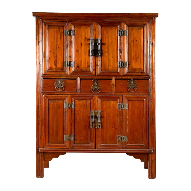 Brown wood antique cabinet with original metal hardware, upper and lower doors, and three central drawers.
