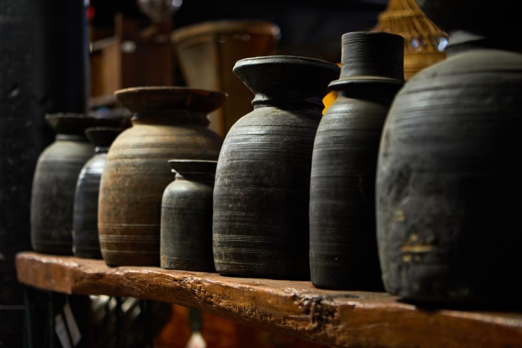 Asian antique row of dark brown wooden pots on a wooden shelf for film and TV set design rental.