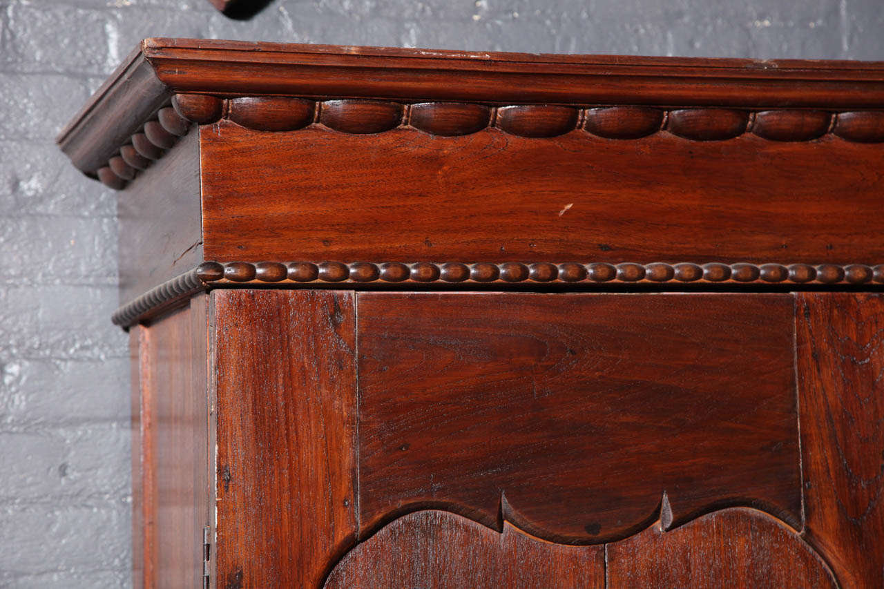 Brown wooden Javanese armoire with two carved doors, 20th century, from Indonesia, against white background.