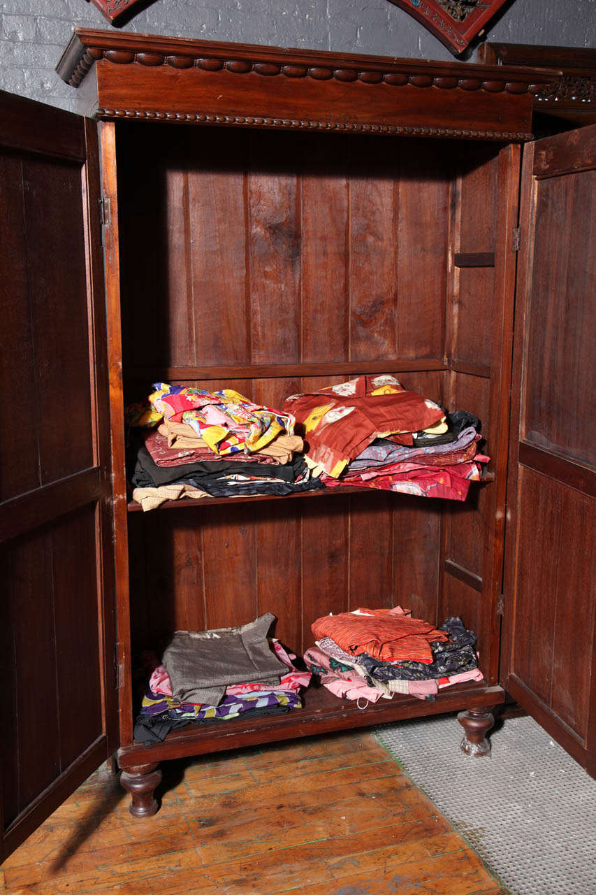 Brown wooden Javanese armoire with two carved doors, 20th century, from Indonesia, against white background.