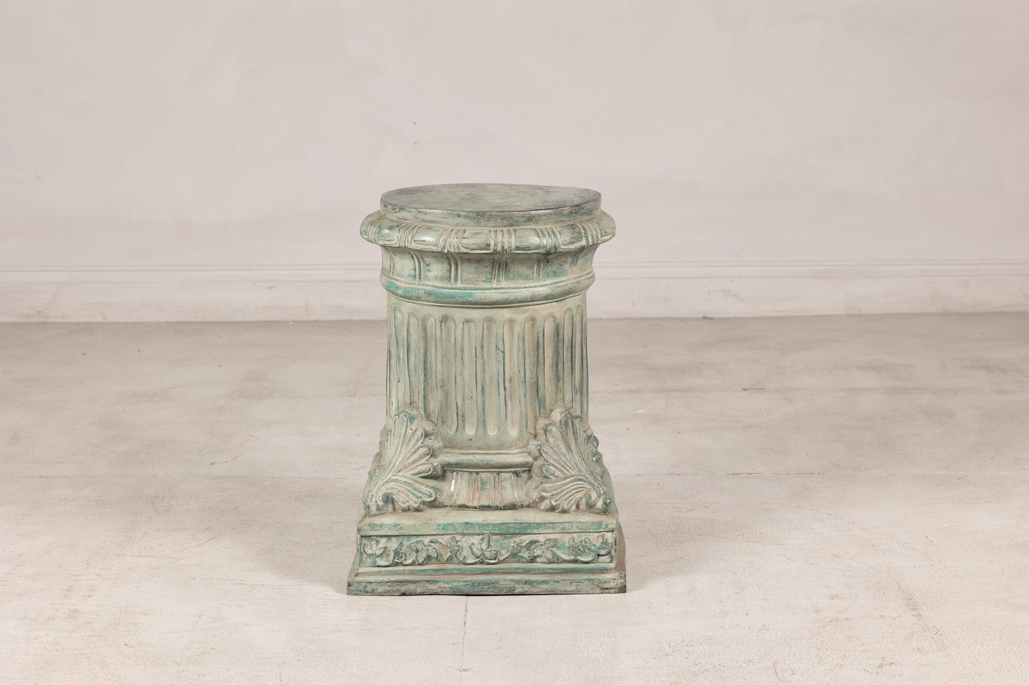 Verdigris bronze pedestal showing fluted shaft and palmette base