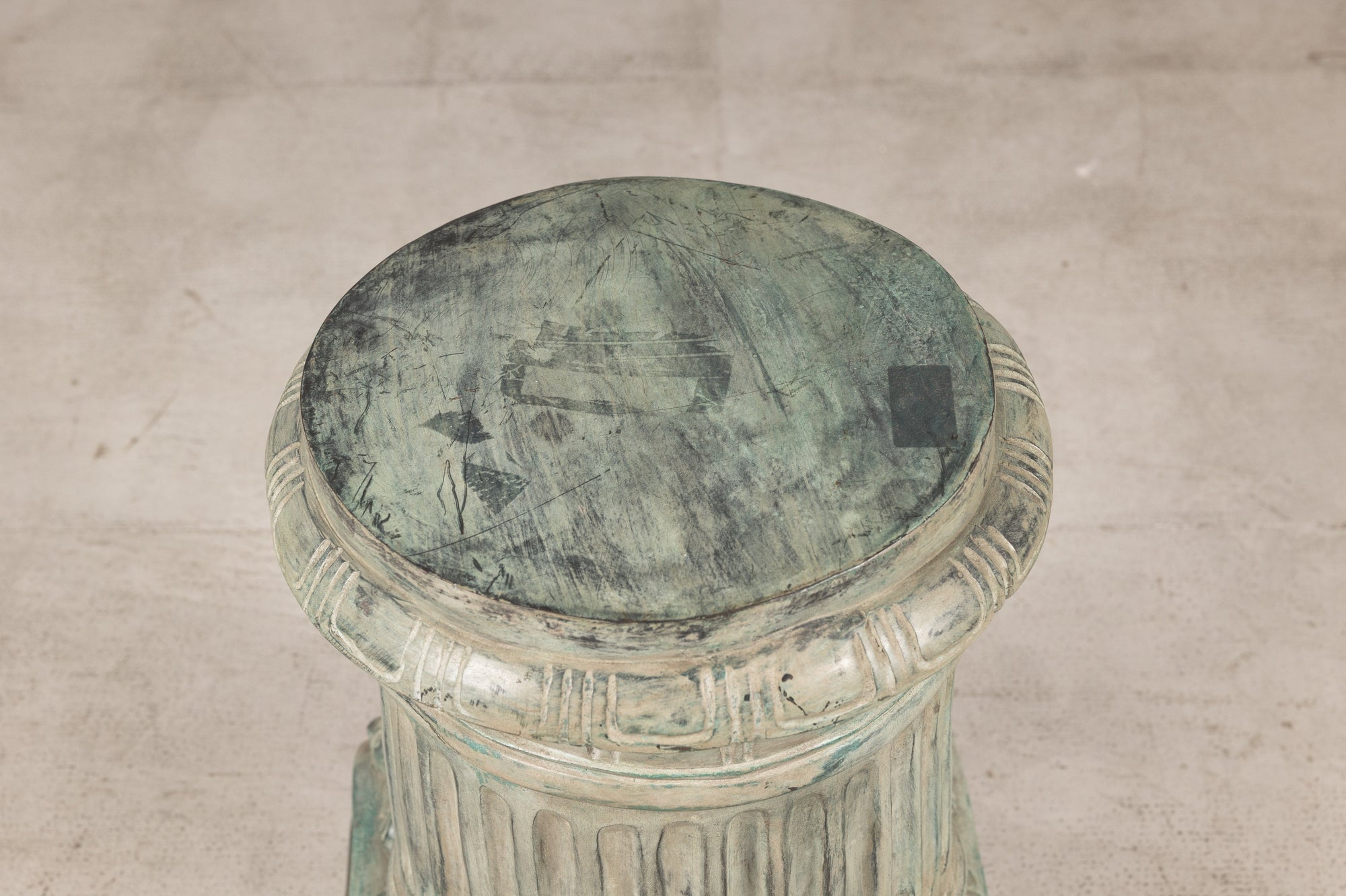 Close-up of round bronze pedestal top with verdigris patina