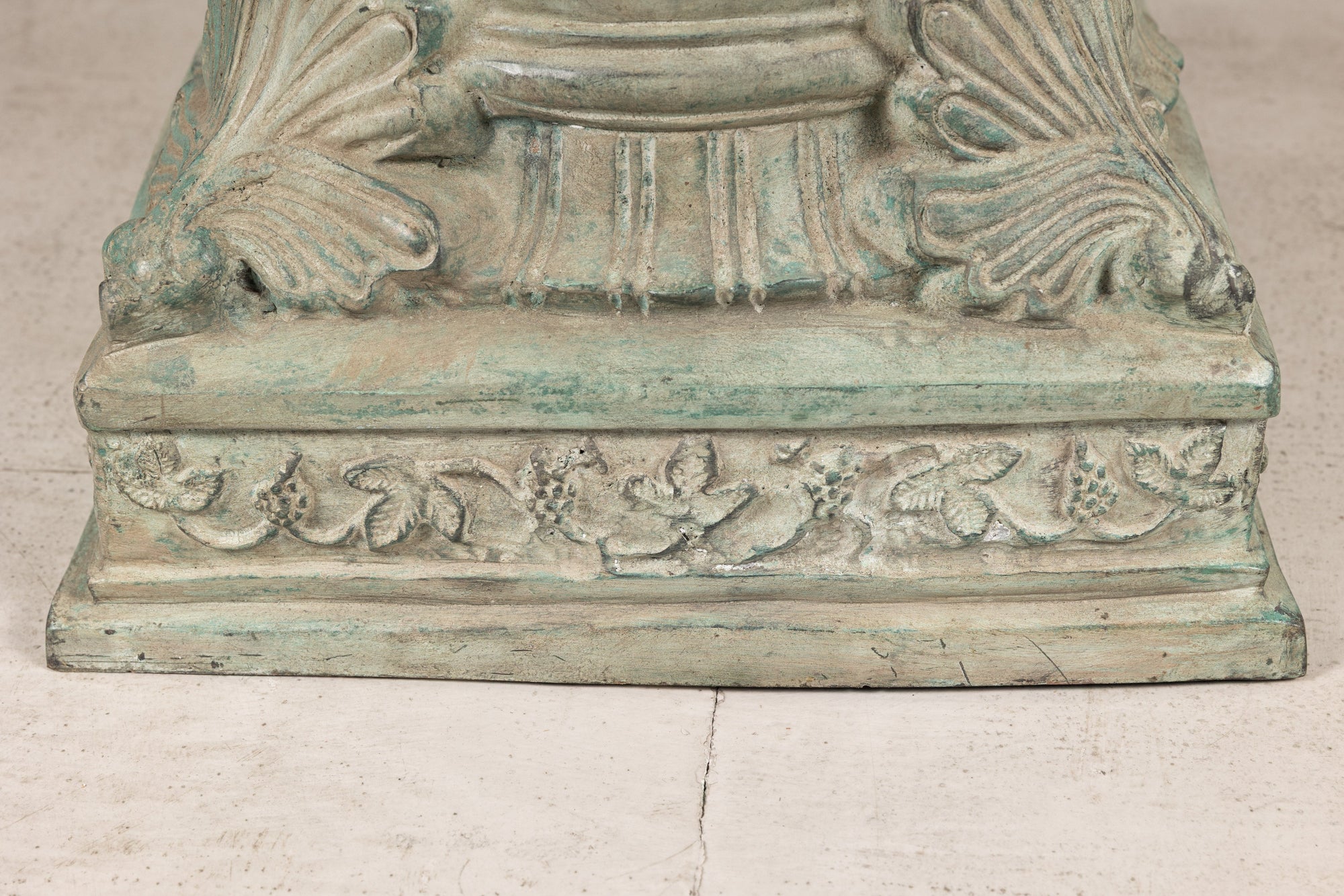 Close-up of bronze pedestal base with scrolling foliate border