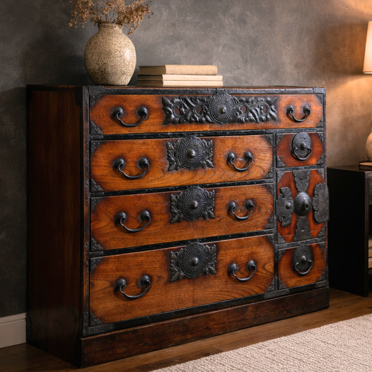 Brown keyaki wood tansu chest with dark metal accents, vase and books on top, Japanese Meiji Period Sendai style.