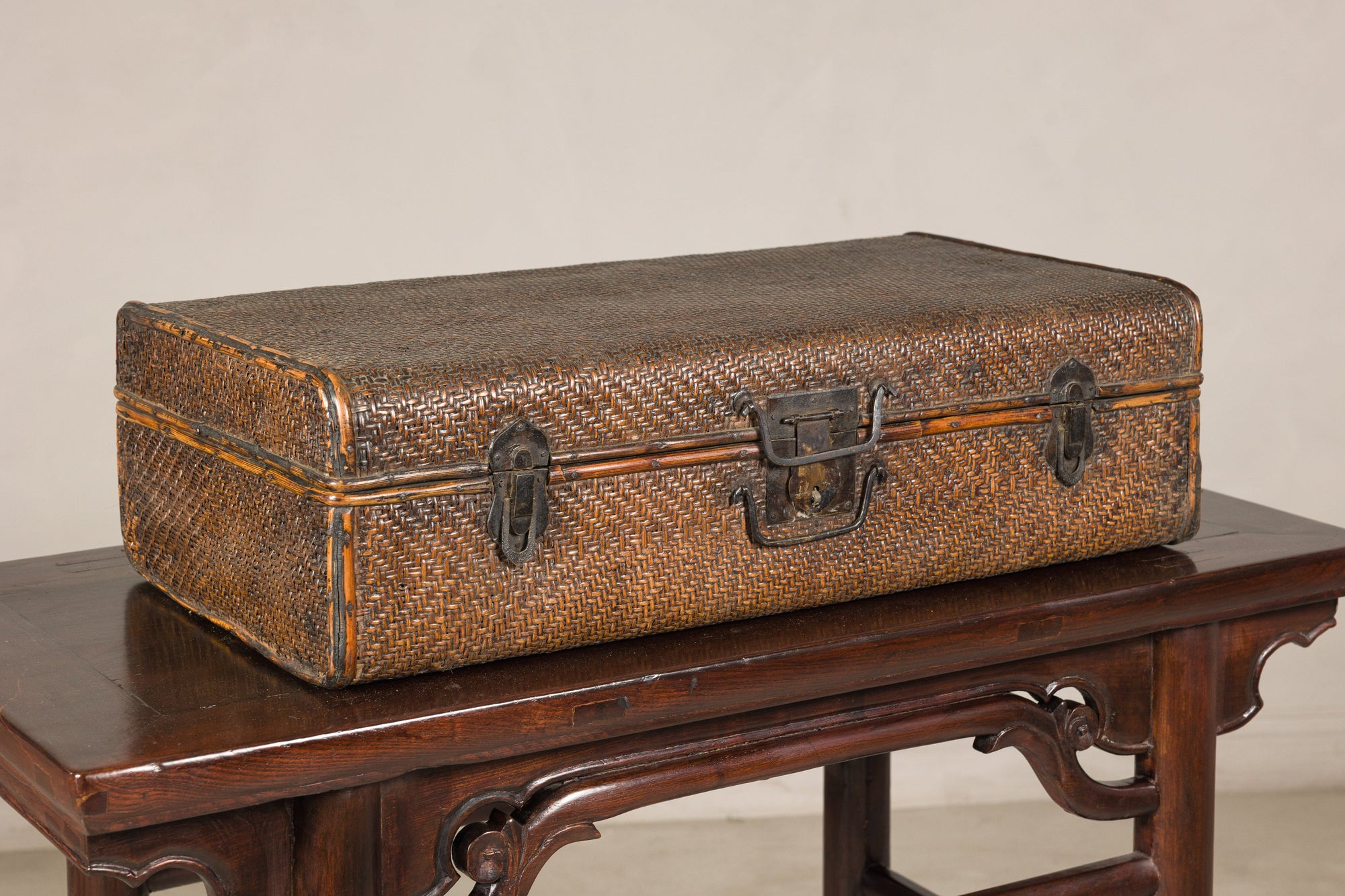 Brown rattan suitcase trunk with iron hardware on a dark wooden table, Late Qing Dynasty style.