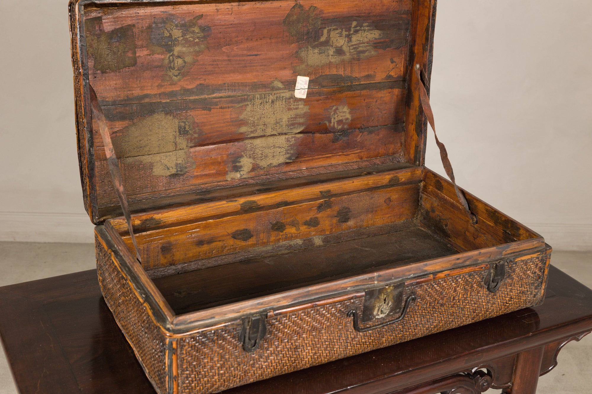 Open woven rattan trunk showing wood-lined interior