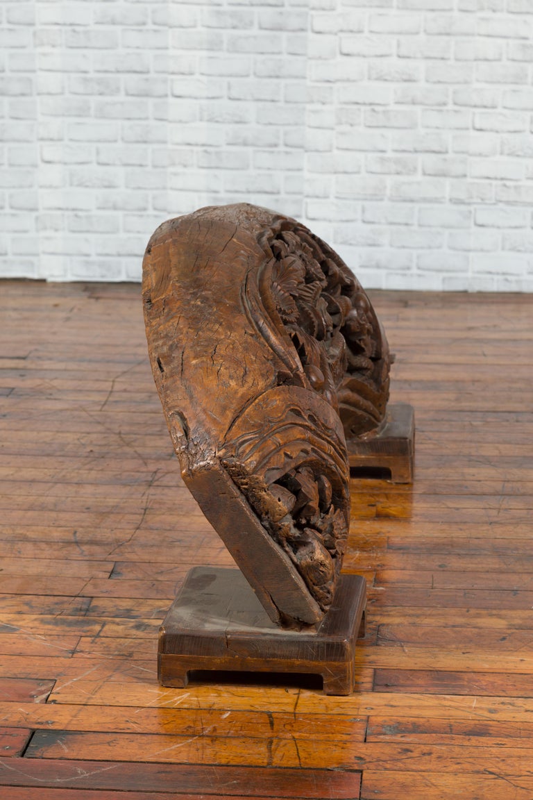 Brown wood arch sculpture with hand-carved animal and floral motifs on a dark antique chest.