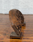Brown wood arch sculpture with hand-carved animal and floral motifs on a dark antique chest.