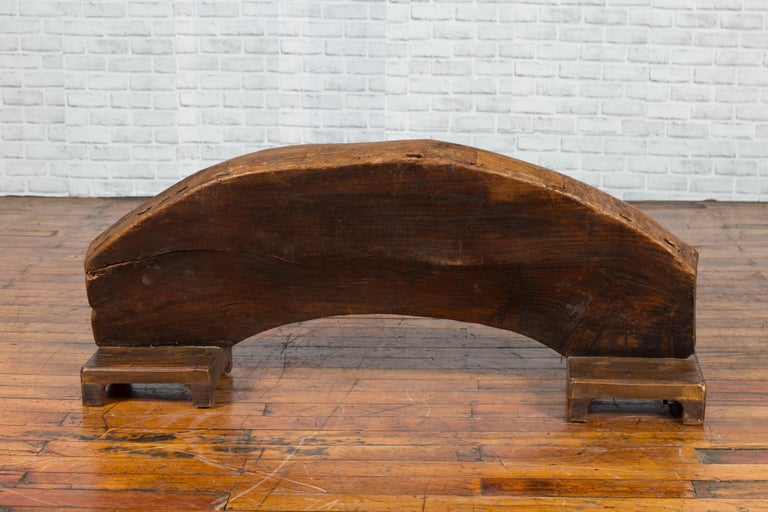Brown wood arch sculpture with hand-carved animal and floral motifs on a dark antique chest.