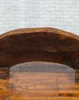 Brown wood arch sculpture with hand-carved animal and floral motifs on a dark antique chest.