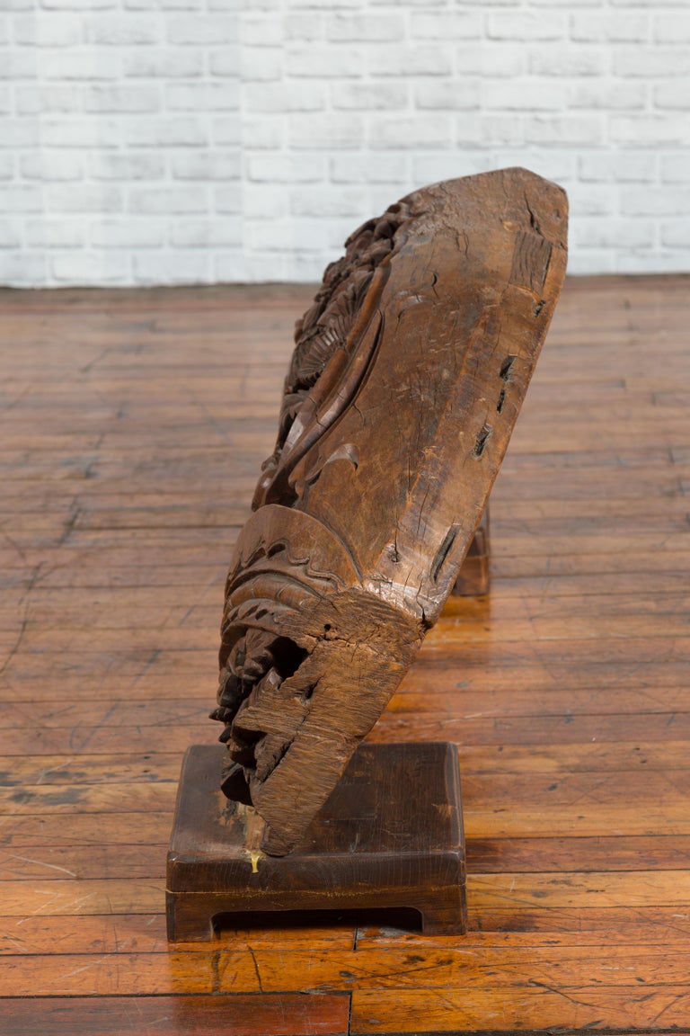 Brown wood arch sculpture with hand-carved animal and floral motifs on a dark antique chest.
