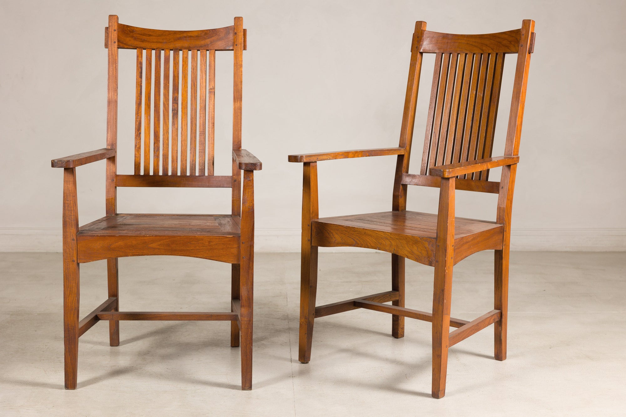Brown teak Dutch Colonial dining armchairs with slat backs, pair shown side by side, vintage 1940s style.