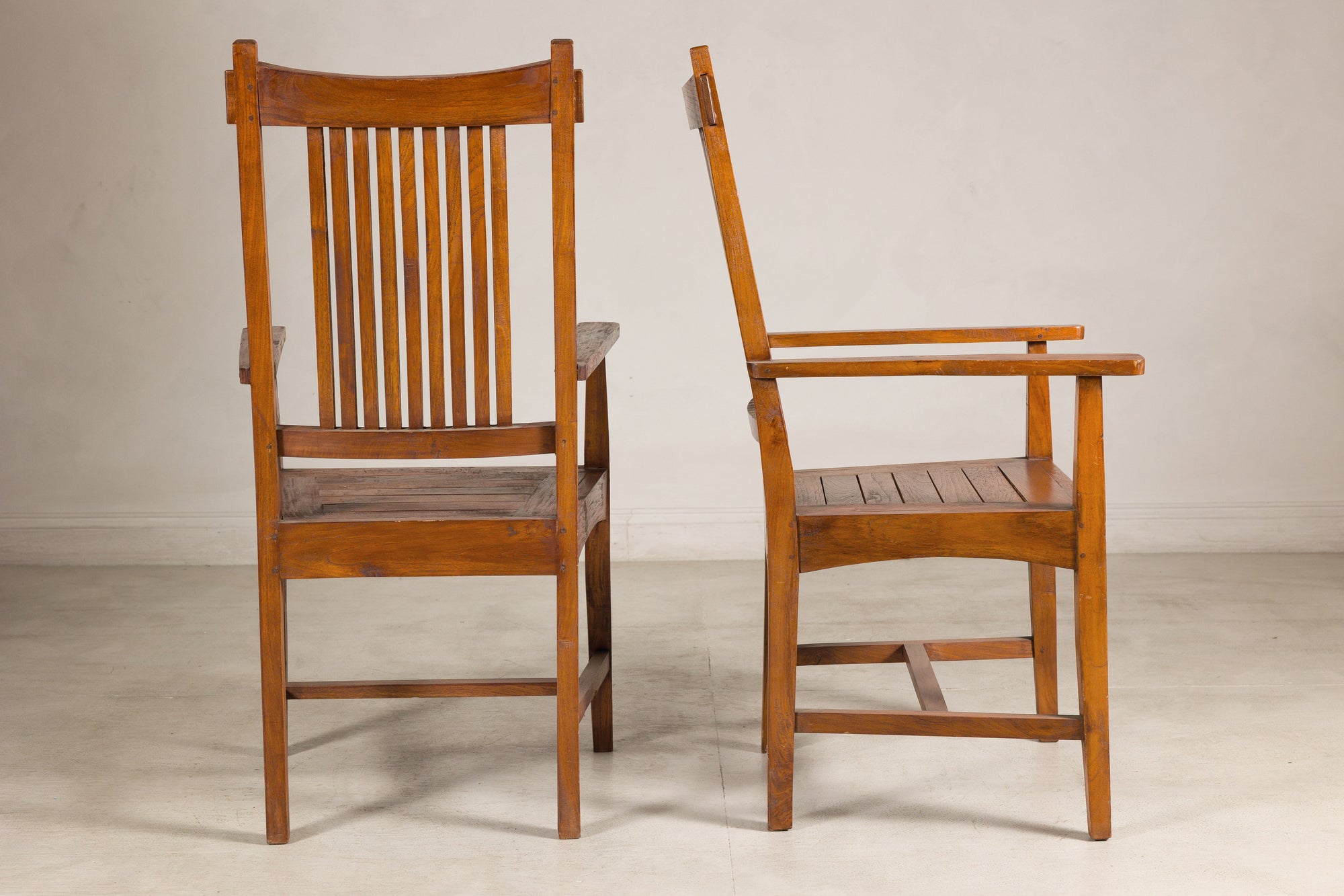 Pair of teak dining armchairs shown from rear and side