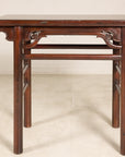 Dark wood Chinese elm console table with carved spandrels and straight legs, Qing dynasty style against plain backdrop.