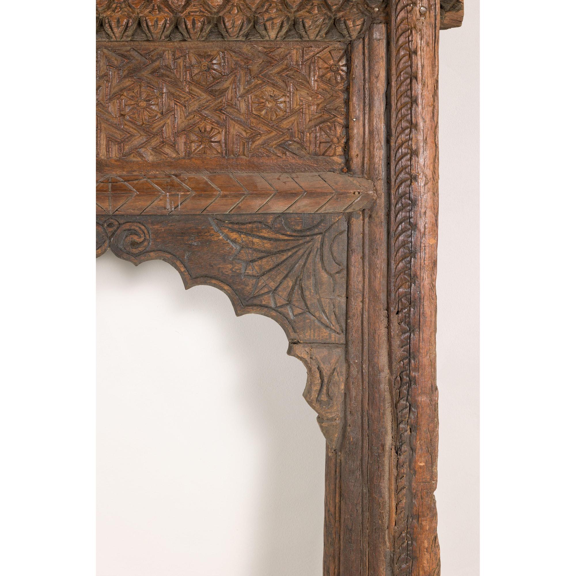 Brown hand-carved wooden Indian architectural frame with scalloped arch, displayed against a white background.