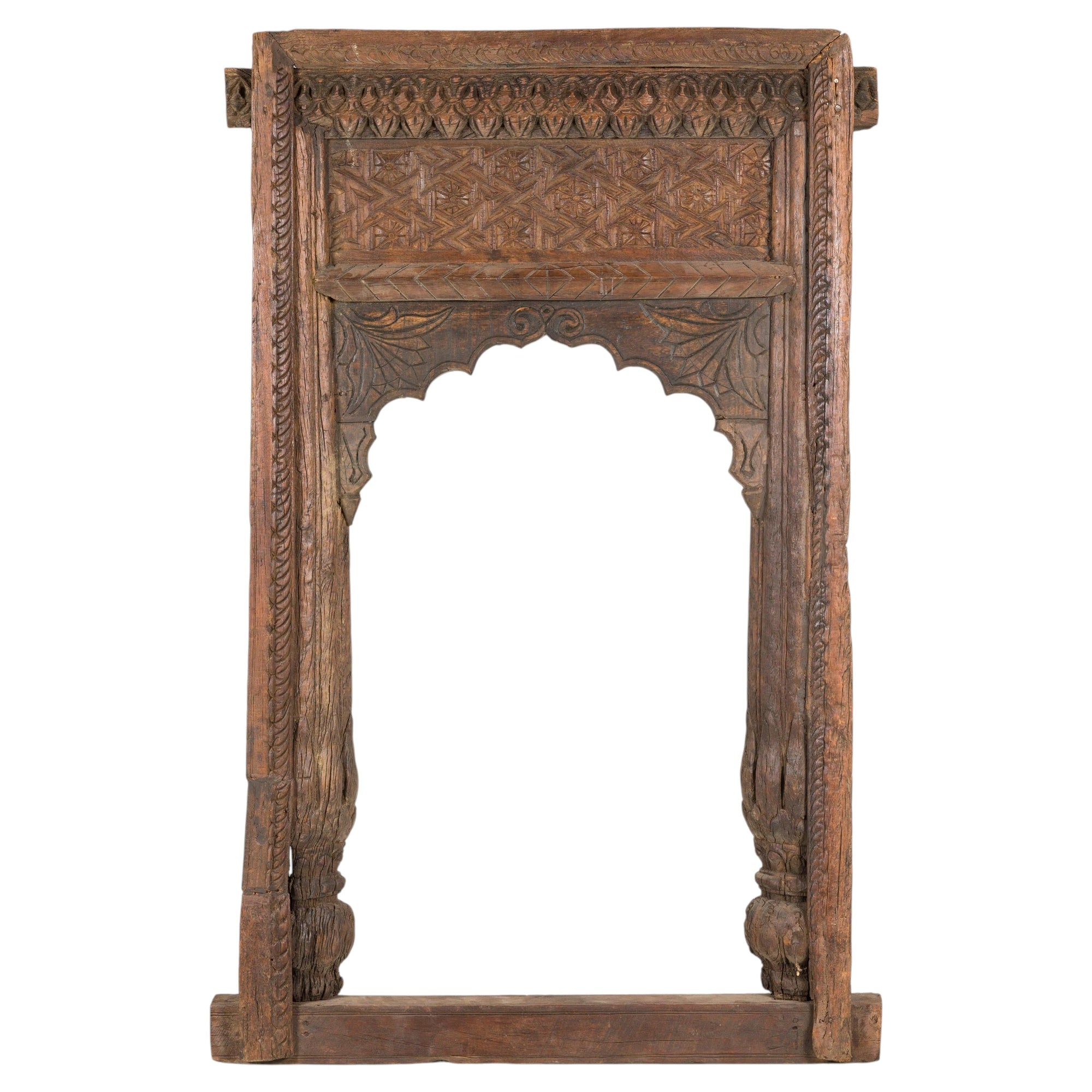 Brown wood hand-carved Indian frame with arched opening, geometric patterns, and leaf details, close-up view.