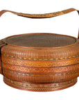 Gold and brown woven rattan Chinese basket with painted lid and curved handles.