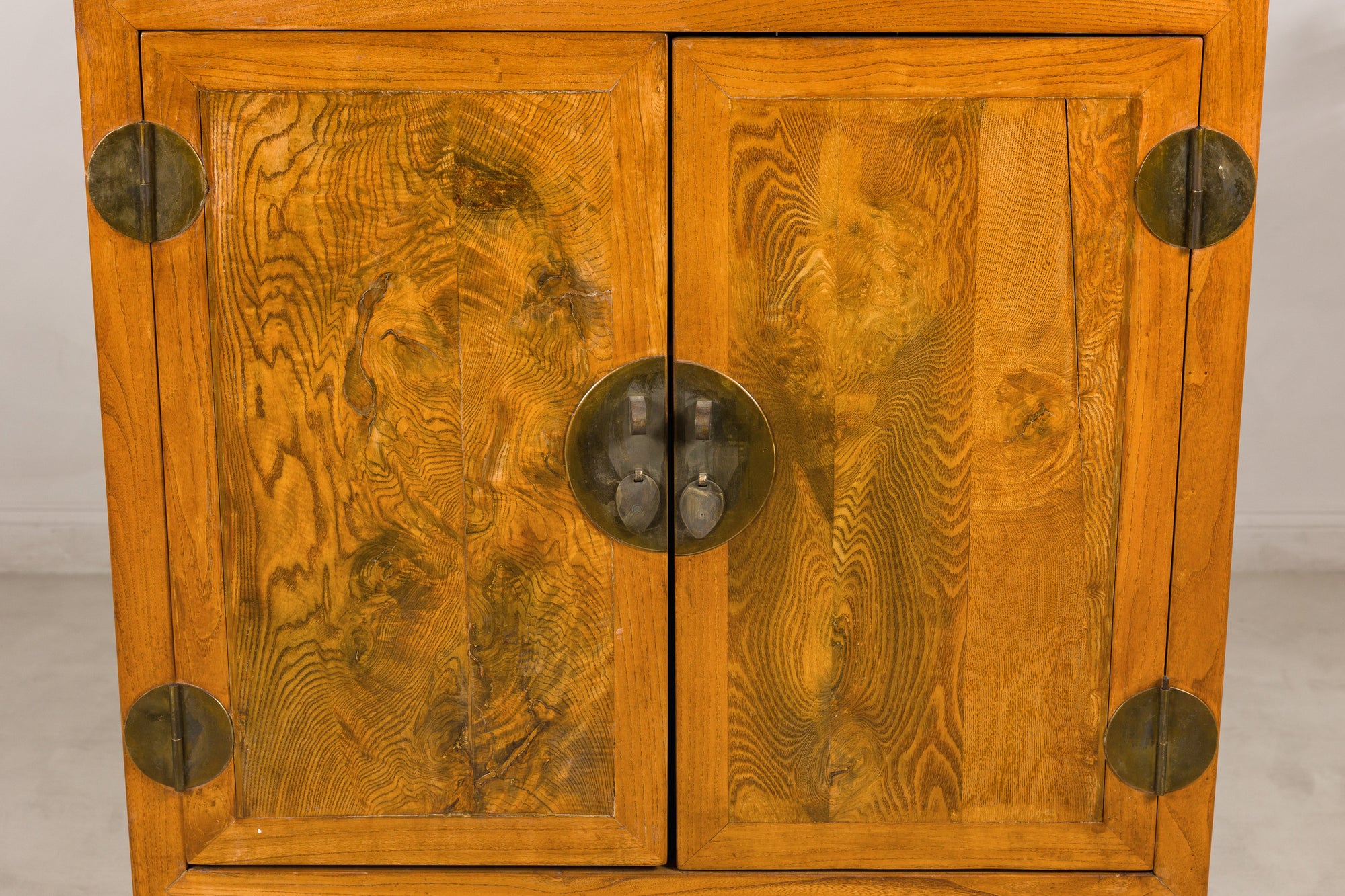 Close-up of figured burlwood doors and round brass hardware