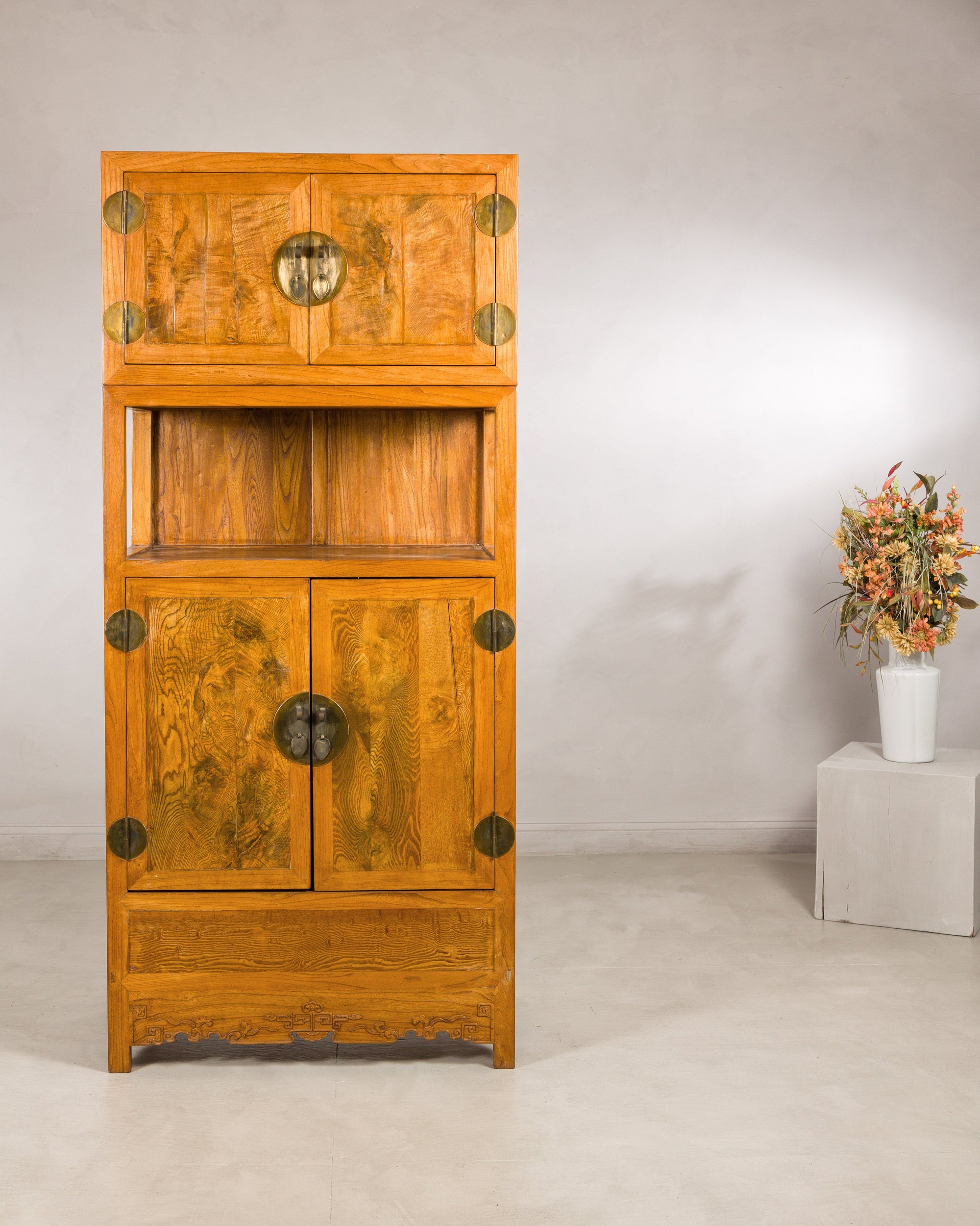 Tall elm and burlwood cabinet styled with a floral arrangement